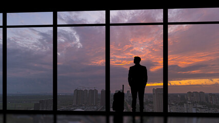 Fototapeta na wymiar The man with a suitcase standing near the panoramic window