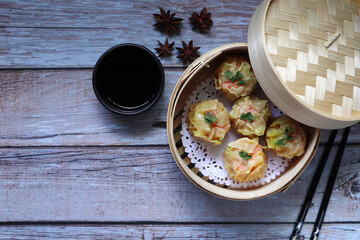 Shrimp Shumai, dumplings are in bamboo steamer box or dim sum basket on the wooden table in the Chinese restaurant during tea time party (yam cha) with close friend in New Year