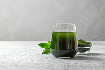 Chlorella healthy detox drink in glass and powder in bowl on a grey background. Close up. Space for...