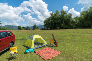 Camping site on grass field with tent and car beside tent. Leisure activity