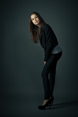 Beautiful teenager girl in the studio in a black tight suit