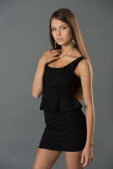 Beautiful teenager girl in the studio in a short stylish black business dress