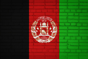 Obraz premium National flag of Afghanistan depicting in paint colors on an old brick wall. Flag banner on brick wall background.
