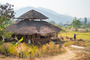 Rural landscape of northern Thailand. A peasant works in a field near his house. Pai, Thailand.