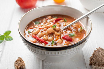 Bulgarian Bean Soup - Bob Chorba, tomatoes, bread and mint on white wooden table. Horizontal orientation. Close up.