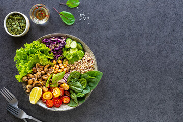 Fototapeta na wymiar Quinoa, mushrooms, lettuce, red cabbage, spinach, cucumbers, tomatoes, a bowl of Buddha on a dark background, top view. Delicious balanced nutrition concept