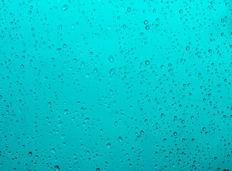 blue rain water drops on a window glass close up with sad clouds in background, drop macro texture ; bad weather backdrop
