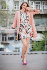 trendy attractive stylish smiling woman walking city street in pink coat spring fashion trend holding purse