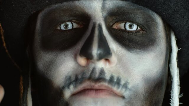 Close-up of scary man face in carnival skull Halloween makeup of skeleton looking creepy at camera
