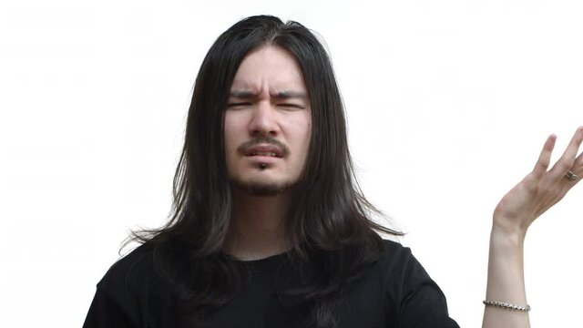 Close-up of confused rocker, punk guy with beard and long hair, shaking head and squinting puzzled, pointing at ear, cant hear you, standing over white background