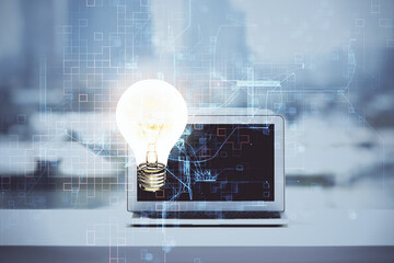 Computer on desktop in office with bulb icon hologram. Double exposure. Concept of idea.