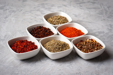 Spices in bowls on a gray concrete background.