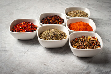 Spices in bowls on a gray concrete background.