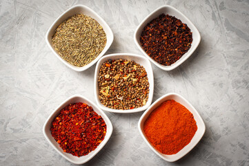 Spices in bowls on a gray concrete background.