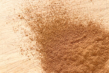 Ground Cinnamon on wooden chopping board.
