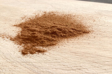 Ground Cinnamon on wooden chopping board.