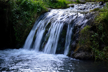 a rapid mountain stream turns into a small waterfall and flows into a lake