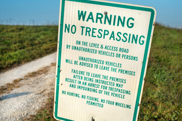 Warning no trespassing sign on gravel road in country