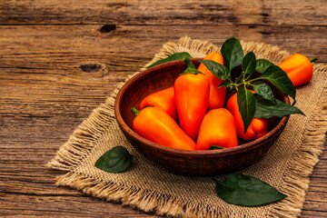 Ripe whole orange mini peppers in clay bowl
