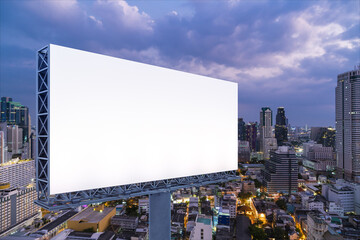 Blank white road billboard with Bangkok cityscape background at night time. Street advertising poster, mock up, 3D rendering. Side view. The concept of marketing communication to sell idea.