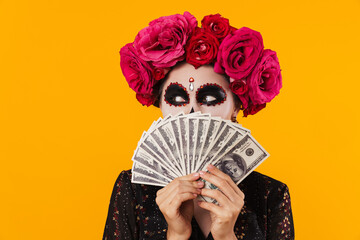 Photo of happy young girl in halloween makeup posing with dollars