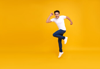 Fototapeta na wymiar Young handsome Asian man smiling and jumping while celebrating success isolated over yellow background.