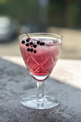 Water with ice and black elder syrup, decorated with elderberries