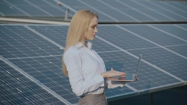 Solar panels and investor with laptop. Business woman with laptop near bule solar cells. Ecological energy for home and business
