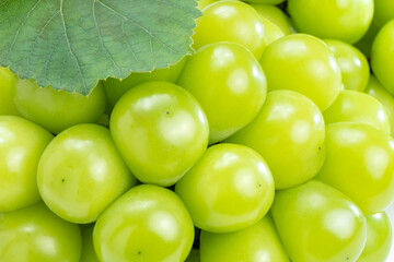 Fototapeta premium Green Grape in wooden basket on bamboo mat isolated on white background, Shine Muscat Grape with leaves isolated on white With clipping path,