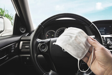 Medical face mask holding on driver hand inside to the car , Coronavirus (COVID-19) prevention concept