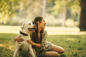 A young woman spends time with her dog in nature, resting after a long walk, sitting on a meadow