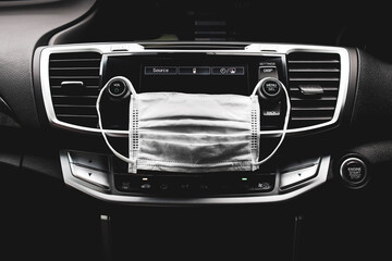 Obraz premium Medical face mask hanging on car audio dashboard inside to the car , Coronavirus (COVID-19) prevention concept