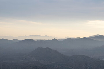 Obraz na płótnie Canvas Paisaje de montañas en la distancia mientras atardece con bruma.