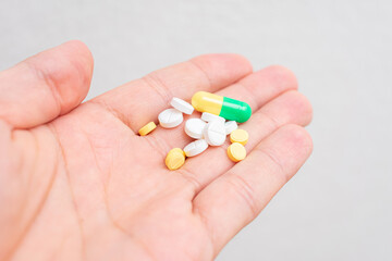 Pills in man's hand, a man's hand and a Handful of different drugs, closeup, cropped image