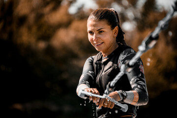 portrait of beautiful smiling woman in wetsuit who holds rope