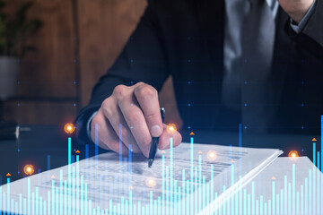 Businessman in suit signs contract. Double exposure with financial chart hologram. Man signing mortgage agreement. Real estate market analysis and investment concept.
