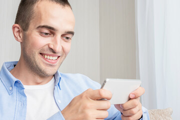 Man with a phone playing mobile games, a guy sitting at home on self-isolation, cropped image, toned