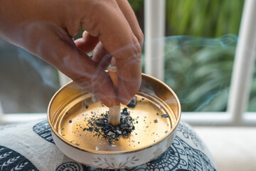 Close-up of a woman putting out a cigarette in a golden ashtray