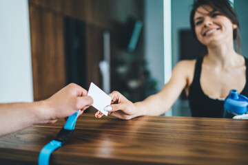 Cheerful caucasian woman talking to employee on reception taking card for access in gym with copy space area for advertising, happy female enjoying service holding key for entering locker room