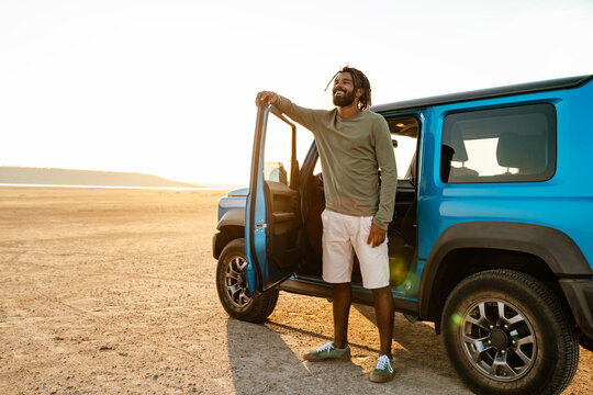 Image of joyful african american man smiling and travelling with car