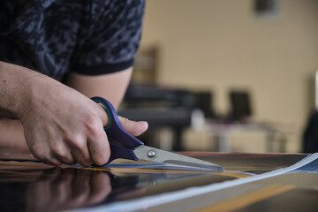 Man cutting print paper with scissors
