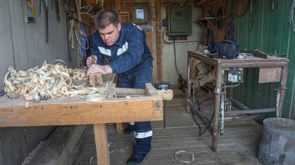 A carpenter planks a Board with an old plane