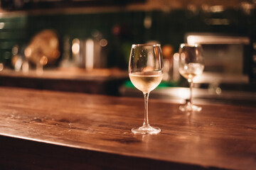 Two glasses of white wine on a wooden table in a cozy dark bar