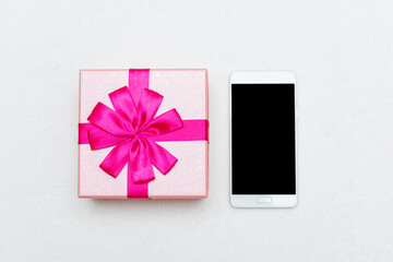 Pink gift and phone, white background, closeup, copy space, top view