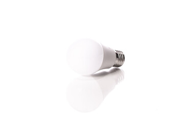 energy-saving LED light bulb lying on glass surface with reflection isolated on white background. Saving electricity, economical electrical appliances