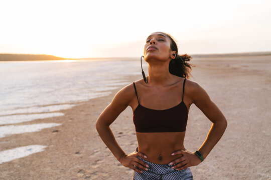 Image of sportswoman listening music with earphones while working out