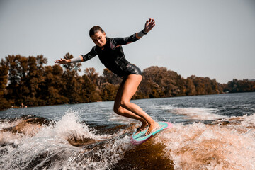 girl riding wave on surf style wakeboard and lifting up lot of splashes