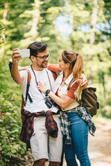 Young couple takes a selfie photo in nature, they look happy and lovely, he looks at her