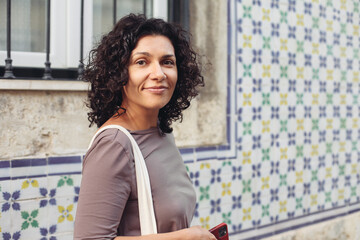 A young pretty woman with an eco bag. Traditional Portuguese building with azulejo tiles on the background.