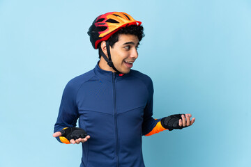 Venezuelan cyclist man isolated on blue background with surprise expression while looking side